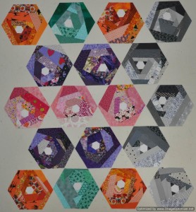 Scrappy Hexie blocks in orange, purple, grey, teal, and pink